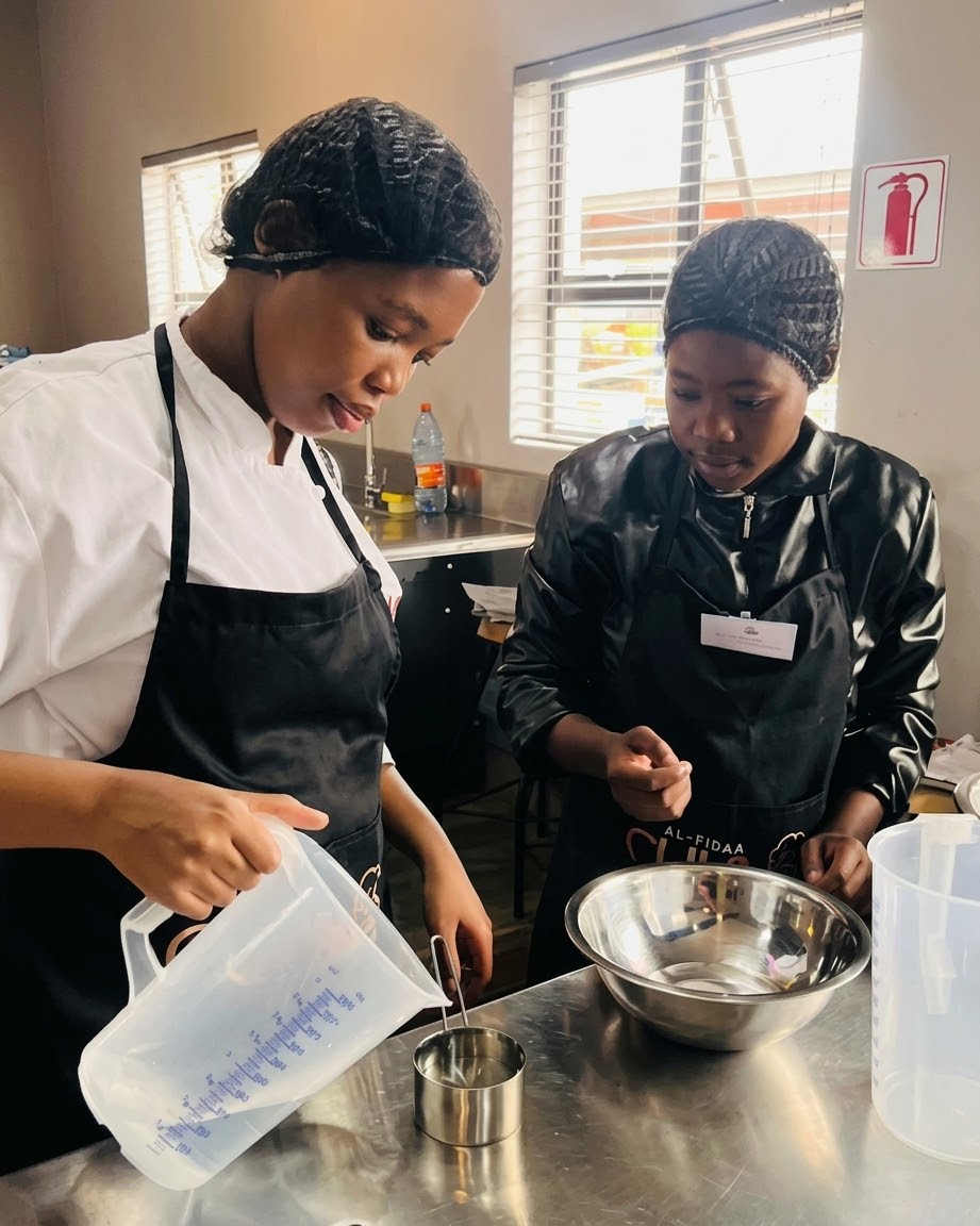 Two cooks measuring ingredients together during a hands-on cooking class